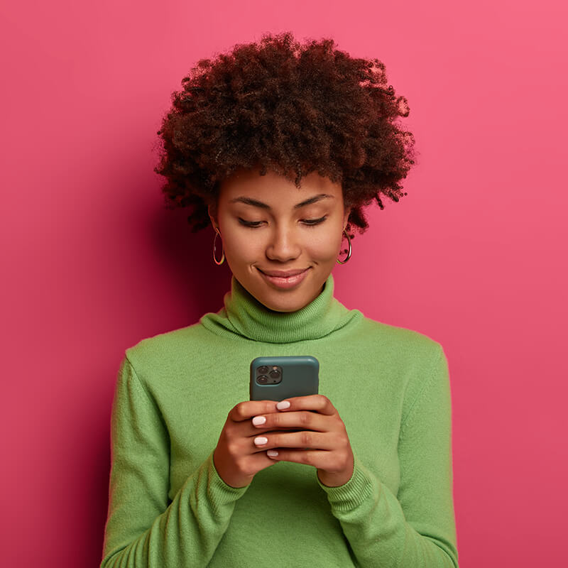 Photograph of a woman smiling while reading her mobile phone